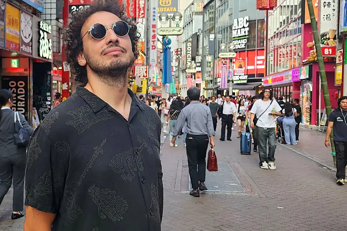 Le guide dans une rue animée de Shibuya, entourée d'enseignes lumineuses